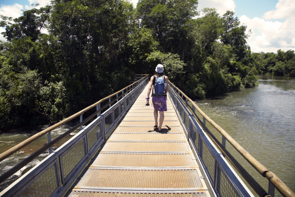 Argentina, Misiones, Iguazu National Park. Girl crossing a bridge over a river near the Iguazu waterfalls – A world heritage site.